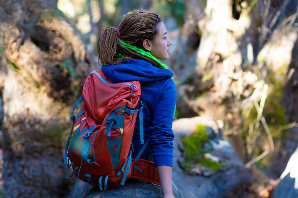 Joyful Girl with Backpack and Hippie style clothing sitting in Forest - 写真・画像
