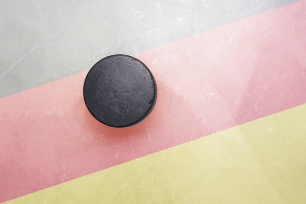 Старая хоккейная шайба на льду с германским флагом
 - Фото, изображение
