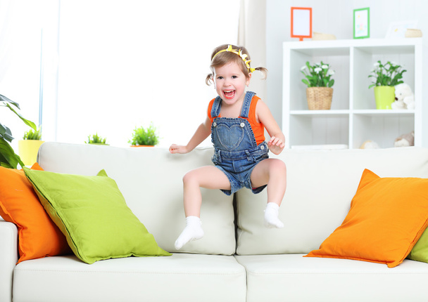 niña feliz jugando y saltando en el sofá en casa
 - Foto, imagen