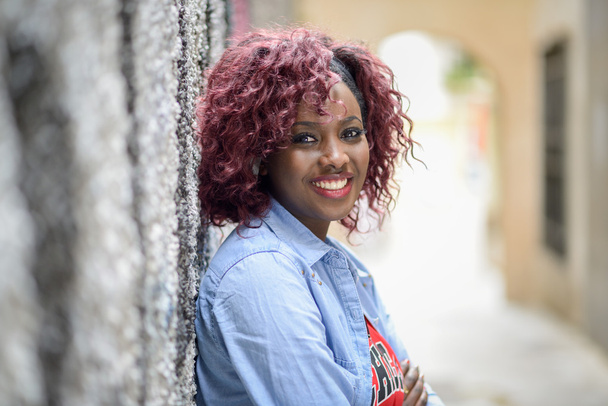 mooie zwarte vrouw in stedelijke achtergrond met rode haren - Foto, afbeelding