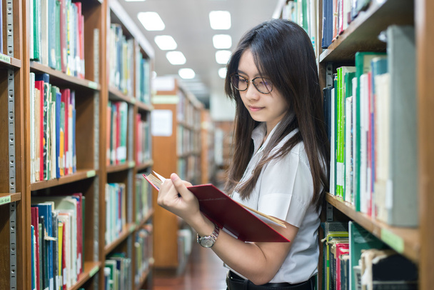 Azjatyckich studentów w mundurach czytanie w bibliotece Uniwersytetu - Zdjęcie, obraz