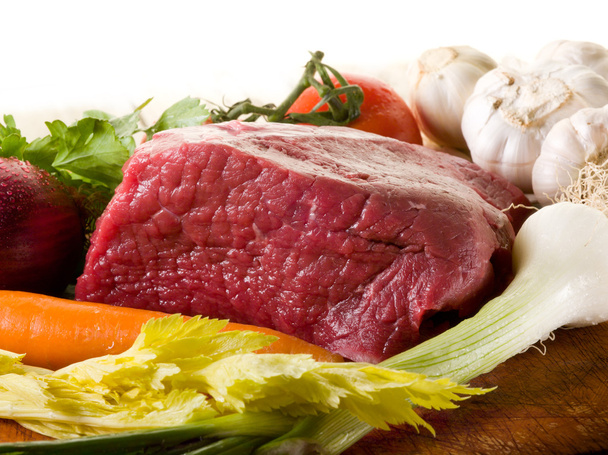 carne com ingredientes vegetais sobre placa de corte
 - Foto, Imagem