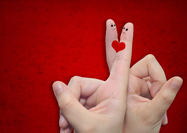 Two hands with fingers and a heart painted over a red paper vintage and grungy background - Photo, image