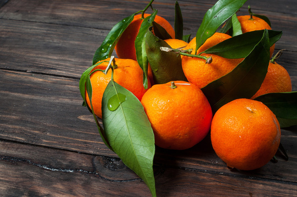 Clementine mandarines with leaves on dark wooden background - Фото, изображение
