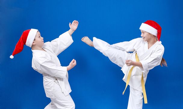 Bambini allegri in berretto di Babbo Natale stanno allenando le tecniche di karate
 - Foto, immagini