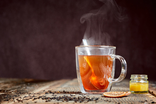 Steaming tea and honey on a wooden table - Фото, изображение