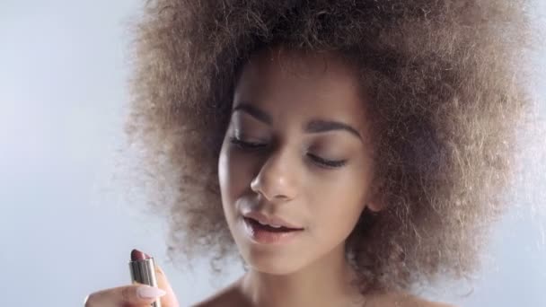 Portrait of a beautiful young African woman applying lipstick. - Video