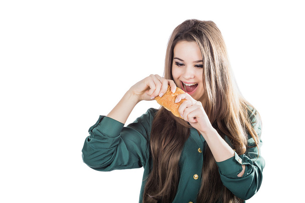 attraktive brünette Frau isst ein Croissant auf isoliertem Hintergrund. - Foto, Bild