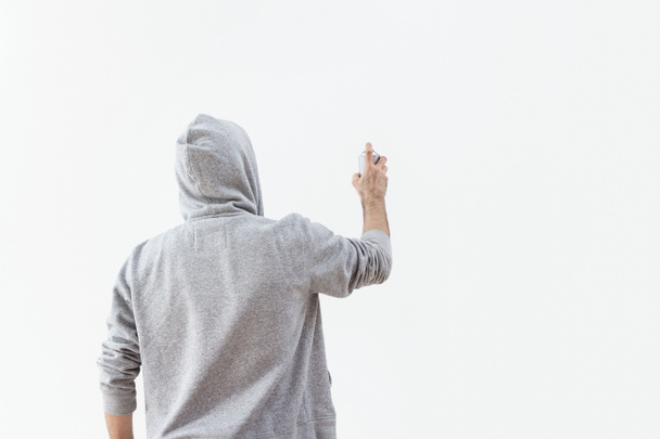 Молодой человек брызгает краской на стену
 - Фото, изображение