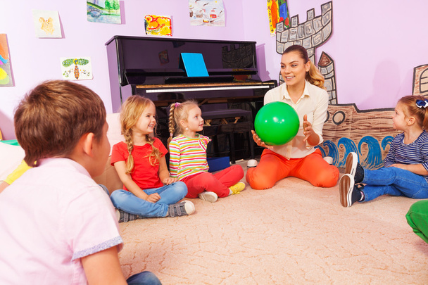 Teacher and kids sit in circle play with ball - Zdjęcie, obraz