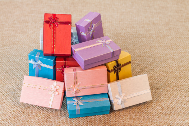 Montón de colorida caja de regalo pequeña sobre fondo de tela de saco
 - Foto, imagen