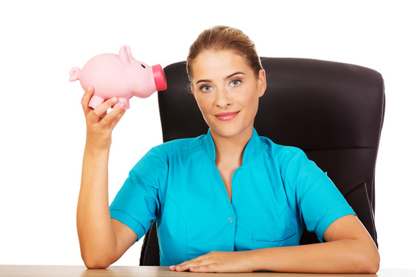 Young female doctor or nurse holding piggybank - Foto, immagini