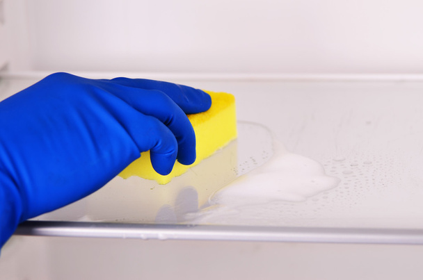 Woman's hand in blue rubber protective glove cleaning white open empty refrigerator with yellow rag.  Cleaning concept. Clean - Φωτογραφία, εικόνα