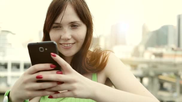 Jeune femme utilisant un téléphone intelligent à l'extérieur
 - Séquence, vidéo