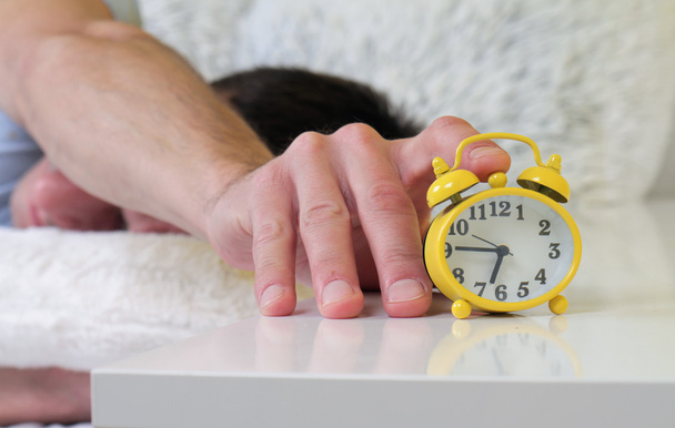 Mann im Bett liegend schaltet Wecker in Großaufnahme aus. Hass wacht früh auf. Selektives Fokusbild - Foto, Bild