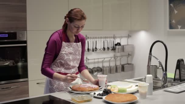 A woman prepares a cake on the kitchen table - Felvétel, videó