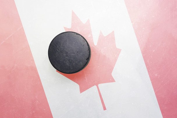 viejo disco de hockey está en el hielo con bandera de Canadá
 - Foto, imagen
