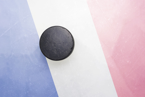 Alter Eishockey-Puck steht mit Frankreich-Fahne auf dem Eis - Foto, Bild