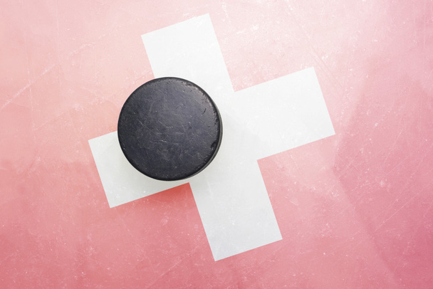 viejo disco de hockey está en el hielo con la bandera de Suiza
 - Foto, Imagen