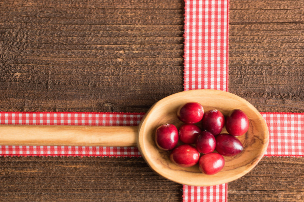 Cranberries em uma colher de madeira
 - Foto, Imagem
