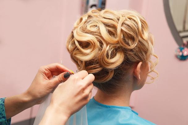 Руки парикмахера делают праздничную укладку волос невесте
 - Фото, изображение