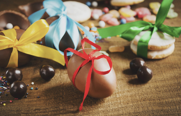 huevos de chocolate en cintas multicolores sobre una mesa de madera
 - Foto, Imagen