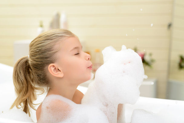 Pleasant little girl playing in bath tube - Photo, Image