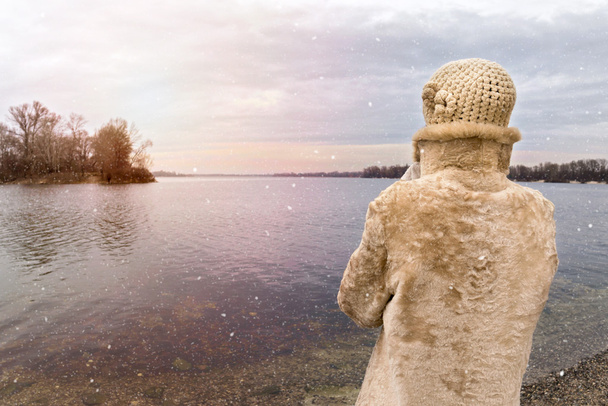 Γυναίκα που ψάχνει στον ποταμό κατά τη διάρκεια μια θλιβερή ημέρα χιονισμένο χειμώνα - Φωτογραφία, εικόνα
