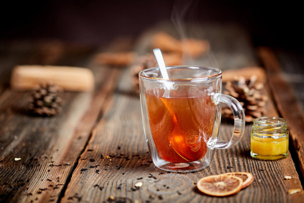 Tè fumante e miele su un tavolo di legno con pigne
 - Foto, immagini