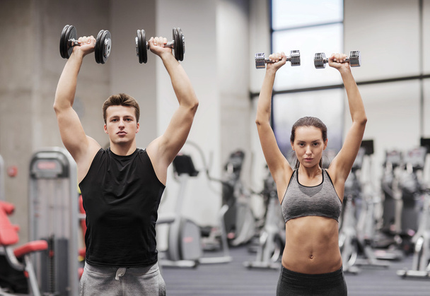 smiling man and woman with dumbbells in gym - Foto, Imagem