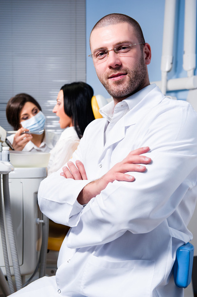 Friendly male dentist with assistant and patient at dental clinic - Foto, afbeelding