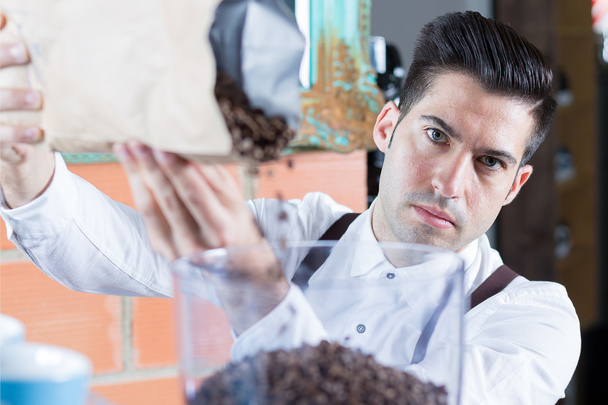 Bartender filling up coffee beans and looking at camera - Photo, Image
