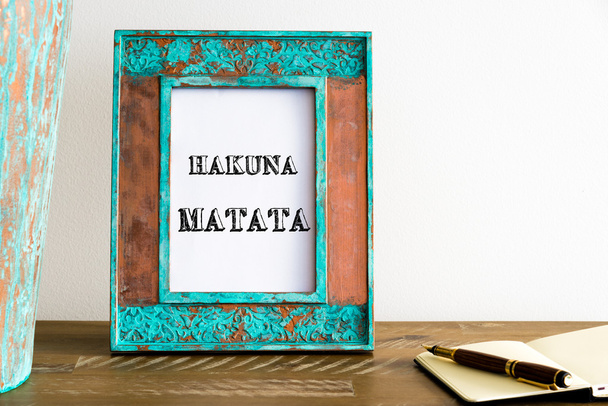 Vintage photo frame on wooden table with text HAKUNA MATATA - 写真・画像