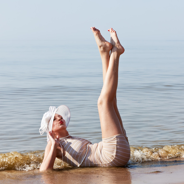 Mujer de sombrero blanco posando contra el mar
 - Foto, imagen