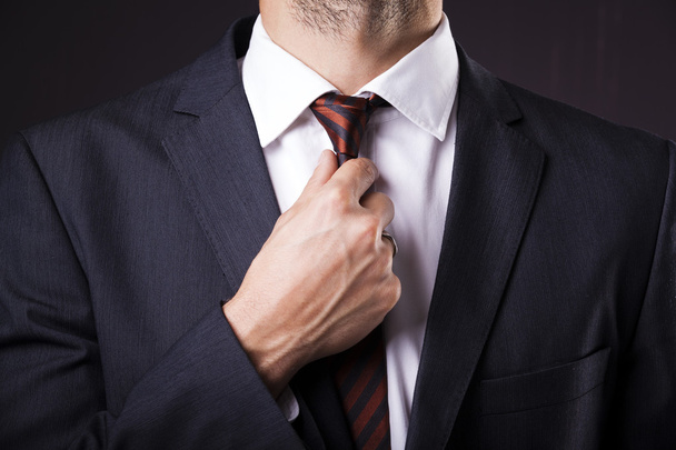 Man in a suit fixing his tie - Photo, image