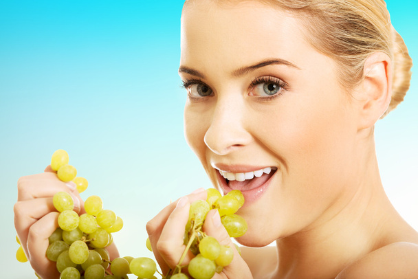 Portrait of nude woman eating grapes - Фото, изображение