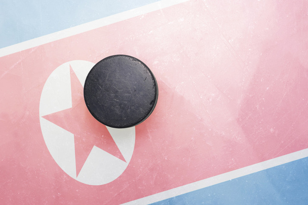old hockey puck is on the ice with north korea flag - Photo, Image