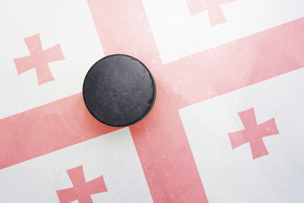 Alter Eishockey-Puck steht mit Georgien-Fahne auf dem Eis - Foto, Bild