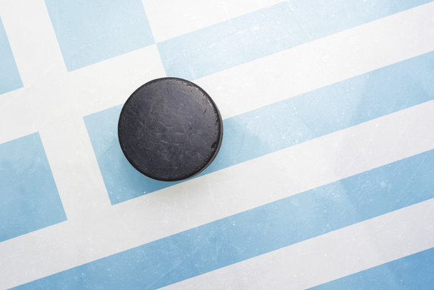 viejo disco de hockey está en el hielo con bandera griega
 - Foto, imagen