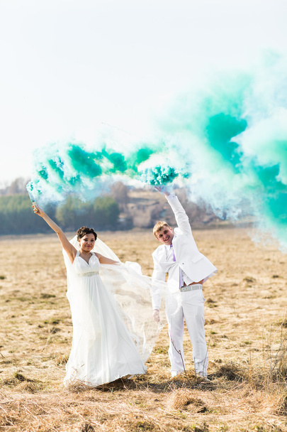 Γαμήλιο ζεύγος με μπλε καπνό στο πάρκο - Φωτογραφία, εικόνα