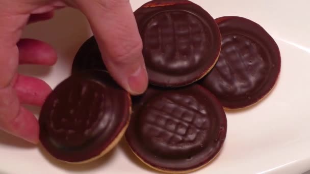 Suklaalla päällystetyt keksit valkoisella lautasella
 - Materiaali, video