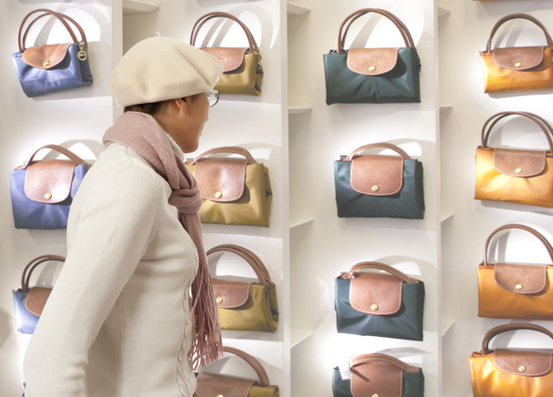 Shopping woman chooses lady's handbag in stor - Фото, зображення