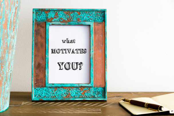 Vintage photo frame on wooden table with text WHAT MOTIVATES YOU? - Foto, afbeelding