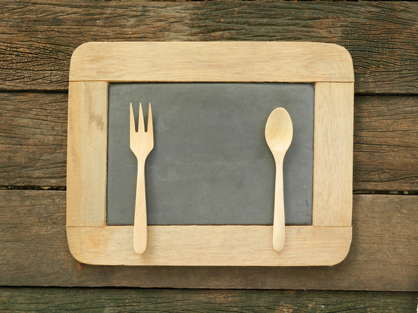 La pizarra de pizarra con cuchara de madera y tenedor en los tablones de madera antiguos
 - Foto, imagen