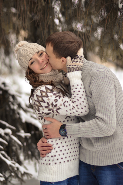 Happy woman, kissed by his boyfriend in the forest. Handsome man kiss her beloved, enamoured, attractive, cheerful, smiling girl in rose cheek. Lovers. - Photo, Image