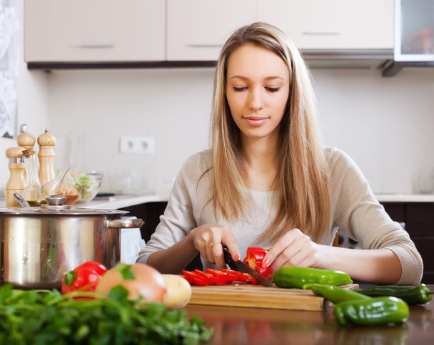 woman slicing red pepper at table   - Photo, image