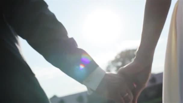 Close-up mladý pár v lásce drží ruce jít k jezeru v zádech svítí - Záběry, video