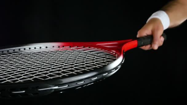 Hand putting three tennis balls on a tennis player's racket, black background - Materiał filmowy, wideo