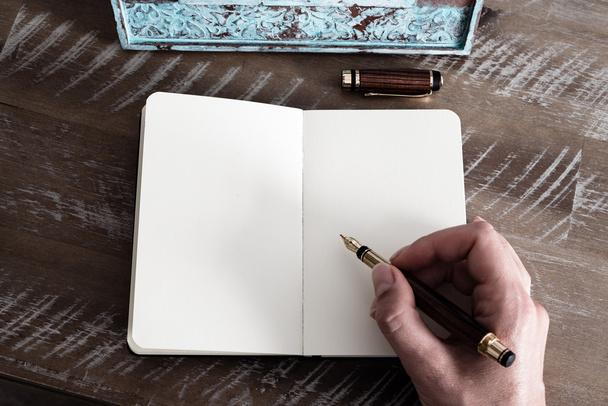 Ρετρό αποτέλεσμα και τονισμένη εικόνα μιας γυναίκας χέρι γράφοντας ένα σημείωμα με μια πένα σε ένα σημειωματάριο.  - Φωτογραφία, εικόνα