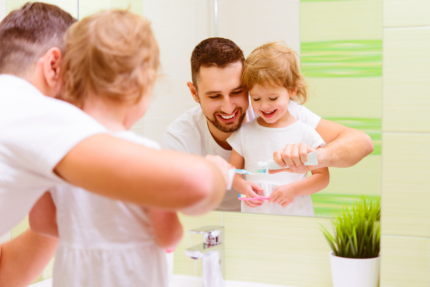 Gelukkig familie vader en kind meisje haar tanden poetsen in BA - Foto, afbeelding